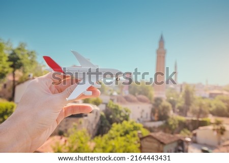 Airplane in hand against the background of the famous Yivli minaret in the old city of Antalya. The concept of travel and cheap air flights