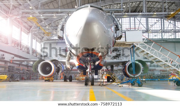 Airplane in hangar, front view of aircraft and\
light from windows