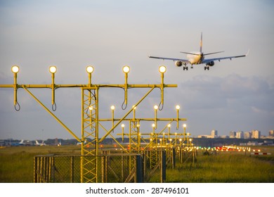 Airplane Is Landing Behind The Runway Lights.