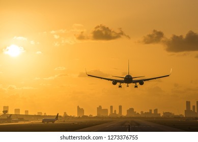 Airplane Landing At Miami International Airport At Sunrise With Miami Downtown Skyline In The Background.