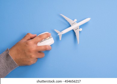 Airplane model and computer mouse on blue background, Online travel booking concept.