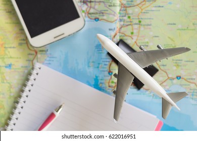 Airplane model, smart mobile phone, notebook and pen on map background, copy space, idea concept for fly trip travel plan on holiday by internet. - Powered by Shutterstock