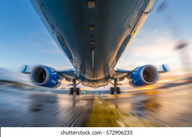 Airplane in motion during takeoff and landing, on a background of sunset and wet runway