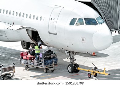 Airplane On Airport Runway Baggage Loading For Departure Nose Cockpit Closeup View Of Modern Passenger Plane At Terminal Gate With Maintenance Worker Person Unloading Luggage From Aircraft On Arrival