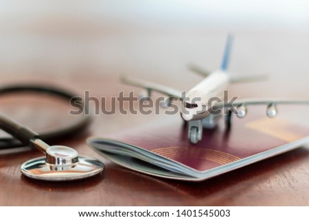 Airplane on top of a passport document and a Stethoscope. Healthcare and travel insurance concept