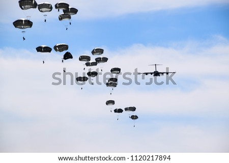 airplane and paratroopers with parachutes in the sky