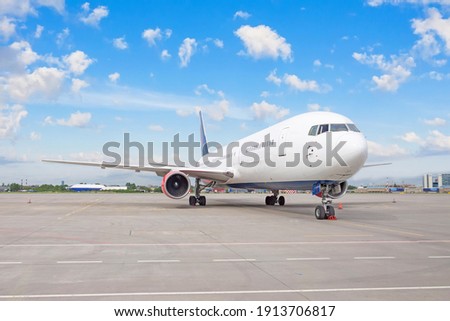 Airplane parked at the airport against the backdrop of a blue scenic skyline with clouds. World aviation concept