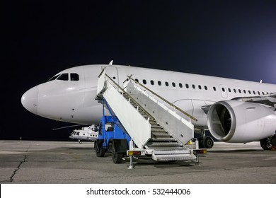 Airplane and passenger boarding steps vehicle at the night airport apron