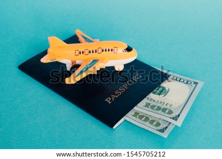 Airplane, passport and dollars on a blue background. Concept - documents and money for travel. Money for a ticket. Cheap low-cost flight.