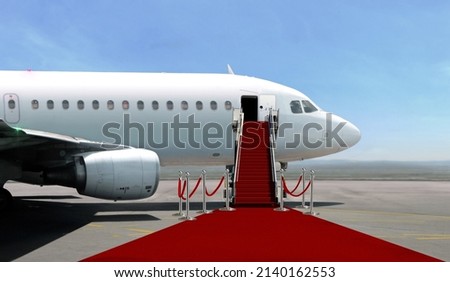 Airplane with red carpet on airport taxiway under bright blue sky