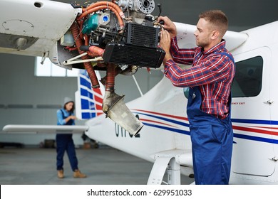 Airplane Service Team Repairing Plane In Hangar:  Modern Mechanic Fixing Disassembled Airplane Turbine