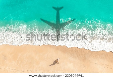 Airplane shadow flying over beautiful exotic tropical beach with woman sunbathing on a sunny cay - Summer vacation travel concept