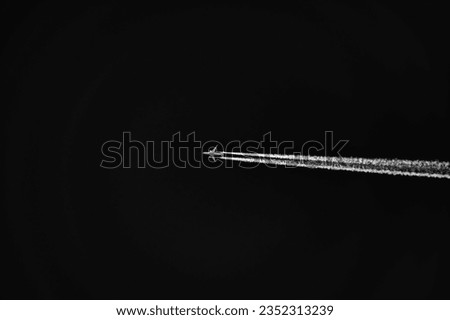 Airplane silhouette high up in the sky with fluffy vapor trail isolated on black. Transportation backgrounds and objects