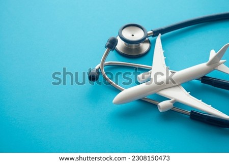 Airplane and stethoscope on blue background with copy space. Going abroad for medical care. Medical tourism is when a person travels to another country for medical care. Healthcare, travel concept.