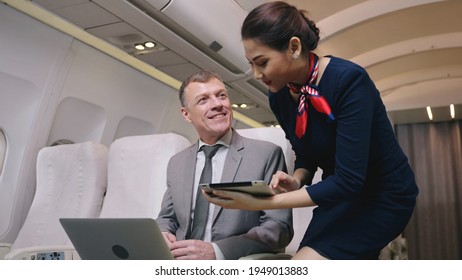 Airplane Stewardess Sending Digital tablet choose food order service on the plane flight, Business class. Flight Attendant Shows Tablet Computer with Menu to Caucasian Male Passenger. They're Inflight - Shutterstock ID 1949013883