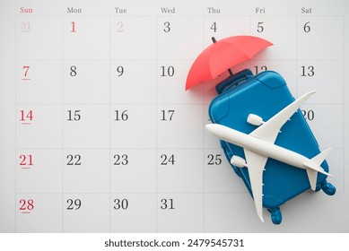 Airplane, suitcase and umbrella on white calendar background. Travel holiday or annual leave travel period for relaxation concept. Period of paid time off (PTO) granted to employees by their employer.