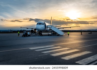 Airplane at sunset - back lit. Airplane being charged and receiving cargo at the airport - Powered by Shutterstock