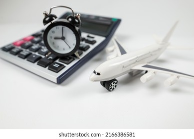 Airplane toy with alarm clock and calculator isolated on white. Flight time. The concept of the cost of air tickets, rising prices for air travel.