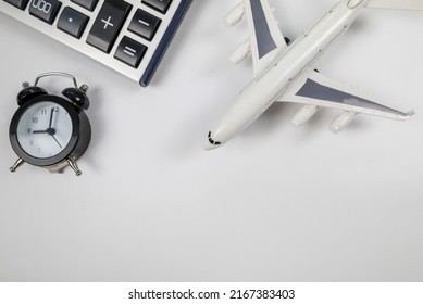 Airplane toy with alarm clock and calculator isolated on white. Flight time. The concept of the cost of air tickets, rising prices for air travel.