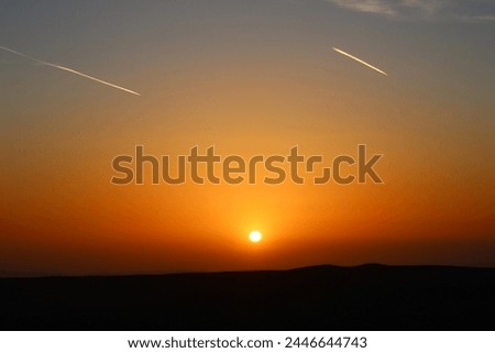 airplane and its trail in the sky. clouds and different color tones in the sky at sunset. Amazing and incredible sunset.