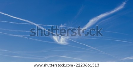 airplane trails of condensed air crisscrossing each other against the blue sky
