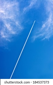 Airplane and vapour trail in blue sky.