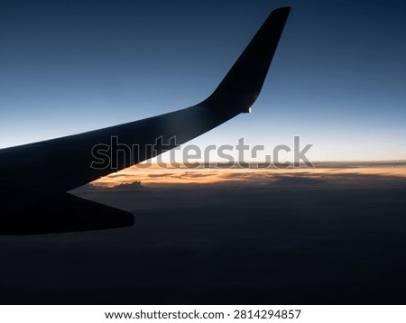 Airplane Window View Above the Clouds at Sunset with Golden Sky and Scenic Aerial Landscape from inflight Perspective