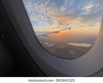 Airplane window view of a dramatic golden sunset sky with wing during flight over Berlin, Germany, July 10th, 2026