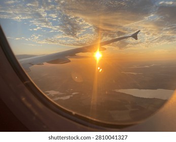 Airplane window view of a dramatic golden sunset sky with wing during flight over Berlin, Germany, July 10th, 2026
