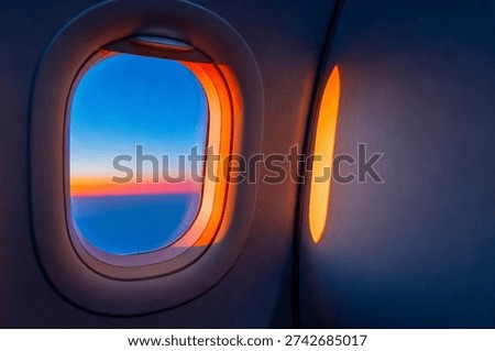 Airplane window view featuring a vibrant sunset over the ocean
