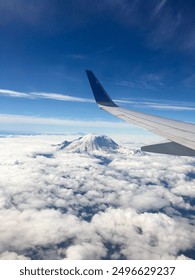 airplane window view with airplane wing and cloudy mountain mount rainier