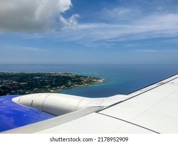 An Airplane Wing Flying Above The Clouds Over Cayman Islands On A Bright Blue Sky Sunny Day.