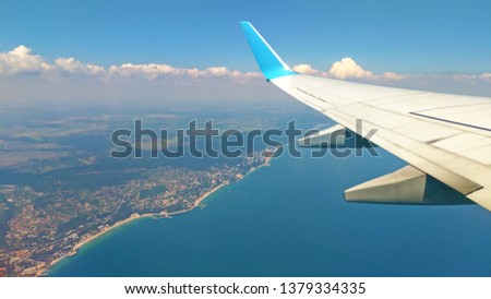 Airplane wing view out of the window on the cloudy sky The Earth and the blue sea background. Holiday vacation background. Wing of airplane flying above the clouds in the sky. Black Sea, Bulgaria.
