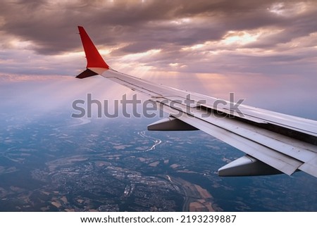 Airplane wing view from the window during a flight on vacation or on business. Landscape with fields in the countryside during the landing approach