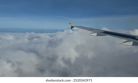 airplane wings from airplane window, white clouds, blue sky - Powered by Shutterstock