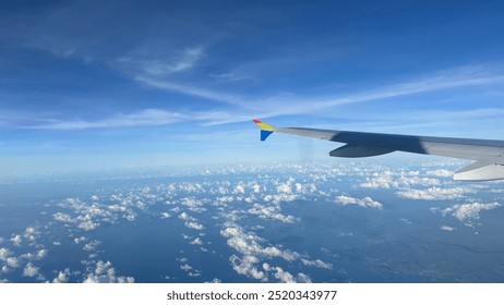 airplane wings from airplane window, white clouds, blue sky - Powered by Shutterstock