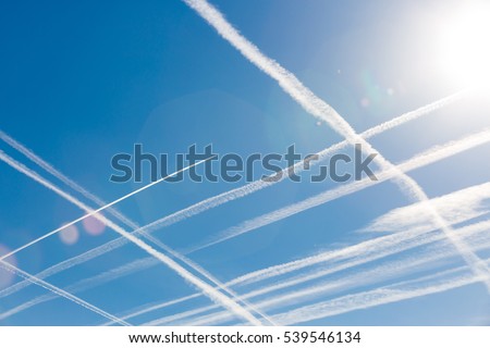 Airplanes in blue sky with Vapor Trail. Condensation trails of planes in the sky. Vertical and horizontal lines in the sky like chessboard or cellular field. Peace. Aviation. Travel concept.