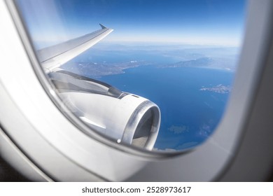 airplane's engine and wing are visible from a window over the Greek Aegean coast