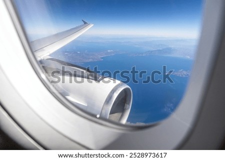 airplane's engine and wing are visible from a window over the Greek Aegean coast
