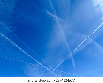 Airplanes leaving diagonal contrails on a clear blue sky