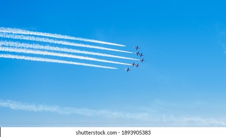 Airplanes on airshow. Aerobatic team performing flight at air show, drawing lines on blue sky.