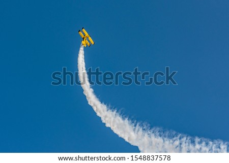 Similar – Red plane with propeller flying upward with white smoke