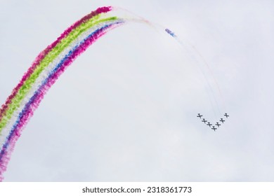 Airplanes on airshow with multicolored colorful bright trails of smoke against blue sky. Aircraft, flying display and aerobatic show, copy space