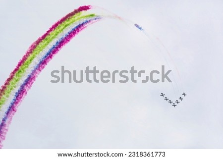 Airplanes on airshow with multicolored colorful bright trails of smoke against blue sky. Aircraft, flying display and aerobatic show, copy space
