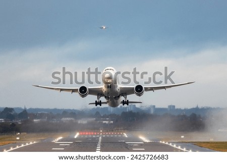 Airplanes taking off and landing during a storm in England - Aircraft leaving on foreground and another one approaching on background - Travel and transportation concepts