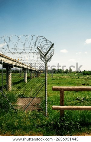 Airport approach lighting structure with barbed wire fence and access stairs under clear blue sky, perimeter security installation.