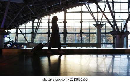 Airport. Beautiful woman with a suitcase at the airport is waiting for her departure. Migration and travel concept. - Shutterstock ID 2213886555