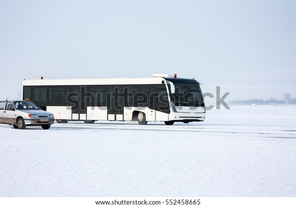 Airport bus and car on\
the winter apron