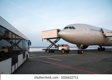 Airport Bus Near The Passenger Airplane On Which The Catering Truck Delivers Food