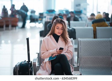 Airport Business Woman Waiting In Terminal. Air Travel Concept With Casual Businesswoman Sitting With Suitcase. Mixed Race Female Professions.